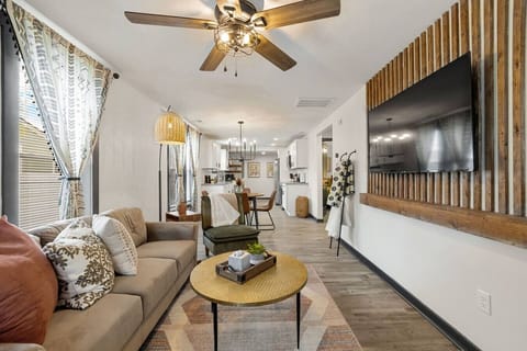 A chic, boho‑inspired living room with plush seating, cozy blankets, modern lighting, and a sleek wall‑mounted Smart TV for effortless relaxation.