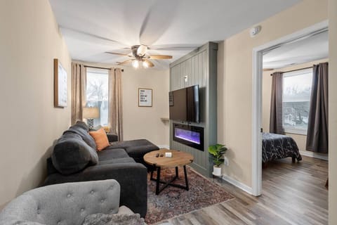 A stylish living space featuring a modern electric fireplace, plush sectional seating, and a large wall‑mounted smart TV—your intimate haven for slow mornings and cozy movie nights.