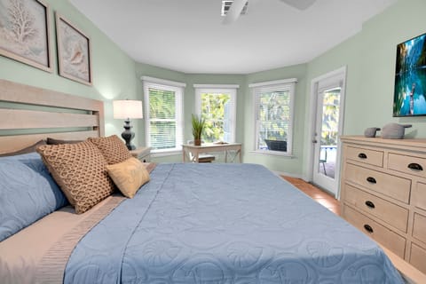 Main Suite: This luxurious retreat features a King bed, nightstands, a full dresser, and a 55" Smart TV. Enjoy a walk-in closet and a dedicated workspace with a desk overlooking the backyard, lanai, and heated pool. The perfect blend of work and rest.