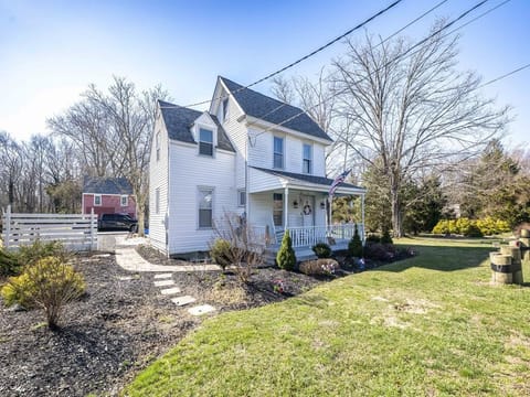 Your home away from home — a charming white clapboard house set against lush greenery, with a cozy cottage tucked alongside.