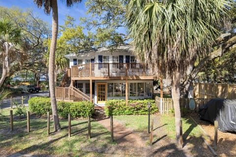 Charming two-story coastal retreat nestled among tropical palms and lush landscaping in a peaceful residential setting.