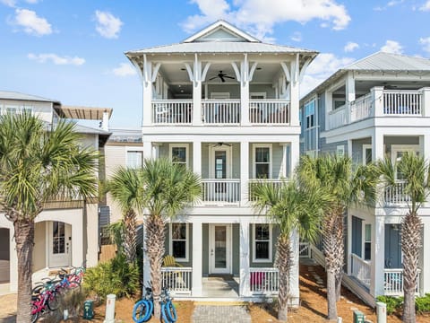 Coastal-style home with palm trees and covered porches creates a perfect beachside retreat atmosphere.