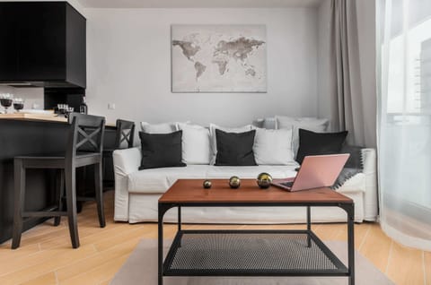 A modern living room features a white sofa with black accent pillows and a wooden coffee table. A world map artwork hangs on the wall above the seating area.