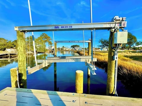 Private backyard dock with boat lift and fillet table, fenced-in backyard, fire pit with Adirondack chairs, hammocks, propane grill, picnic table, outdoor shower, expansive waterfront back deck with table and seating, neighborhood boat ramp and dock