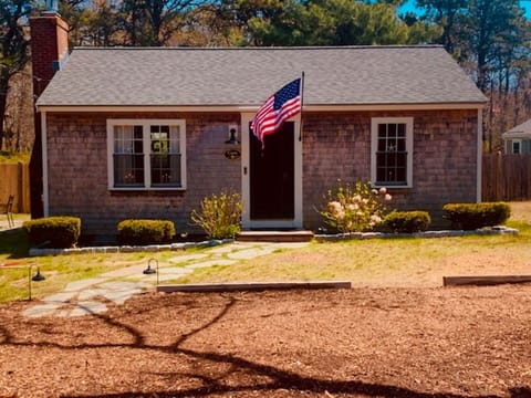 Cozy, welcoming Cape Cod style cottage with a stone walkway and beautiful greenery