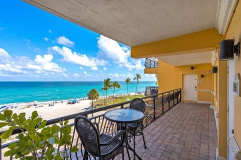 Your private oceanfront balcony on the 4th floor — with a bistro table, wicker chairs, and a sweeping view of the beach and Atlantic. Morning coffee or sunset drinks have never looked this good.