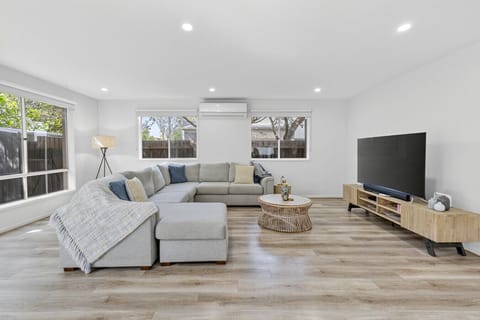 Spacious living room with large sectional sofa, smart TV, and plenty of natural light