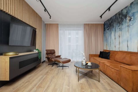 A modern living room with a large sofa and a sleek media wall. The combination of textures, including wood and soft fabrics, adds depth and comfort to the space.