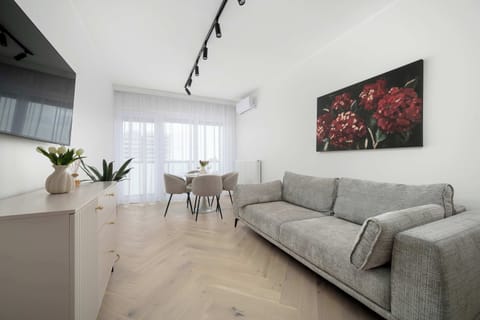 A stylish lounge area with a long sofa and a low TV unit, complemented by subtle decorative elements. The space feels uncluttered and calm, with a focus on comfort.
