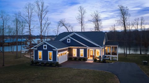 Exterior - A blue-hour aerial from the front captures Summer's Landing: craftsman blue, covered porch, and the lake behind.
