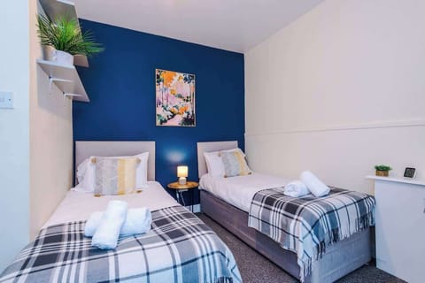 Charming bedroom with two single beds that convert to a double, stylish blue accents, and cozy touches for a relaxing stay.