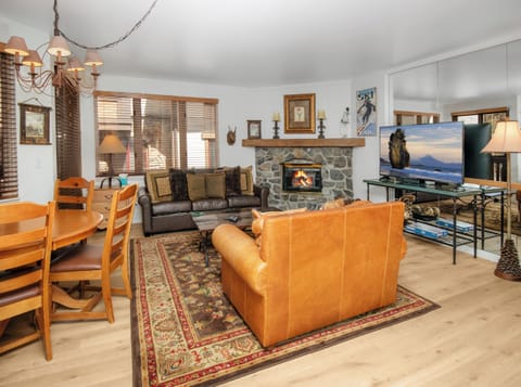 Cozy up in your spacious living room where a crackling stone fireplace, rich leather seating, and warm wood accents create the perfect mountain retreat for unwinding after a day of adventure.