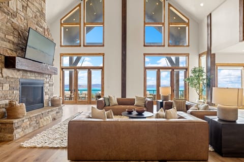 Sink into plush seating and soak in stunning lake views through floor-to-ceiling windows. The stone fireplace adds warmth while you unwind in this light-filled retreat.