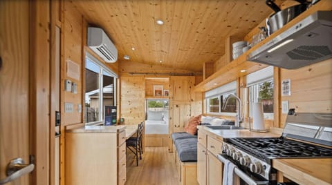This interior combines cozy charm and practical design with a full kitchen, built-in seating, and a comfortable sleeping area beyond.