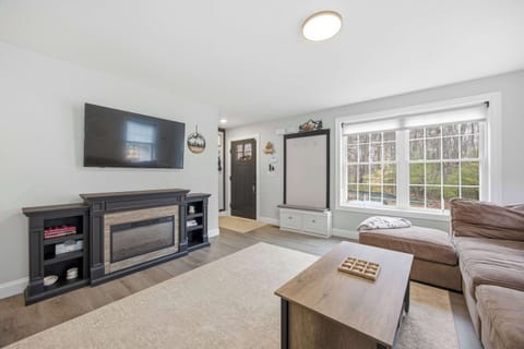 The living room anchored by a wall-mounted 55" smart TV and electric fireplace — a natural spot for movie nights or rainy-day hangs.