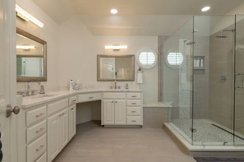 Luxurious master bathroom with a double vanity and glass shower.
