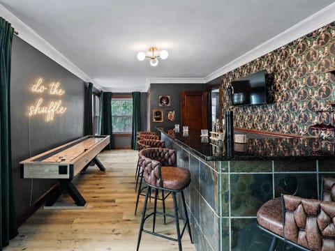 Stylish event room w/ bold wallpaper, bar seating & warm lighting — made for memorable gatherings.
