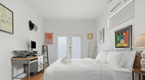 A peaceful, polished retreat featuring luxe white linens, warm wood floors, stylish artwork, and space to rest or catch up on work.