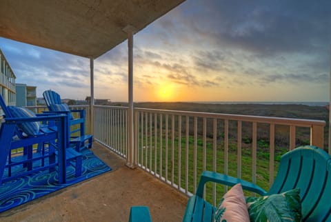 Private balcony with blue Adirondack chairs overlooking the coastal dunes.
