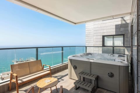 Soak beneath open skies as ocean breezes drift across this serene balcony retreat.