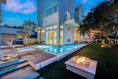 Modern luxury villa with sleek pool deck and elegant outdoor fireplace, perfect for evening gatherings under the stars.
