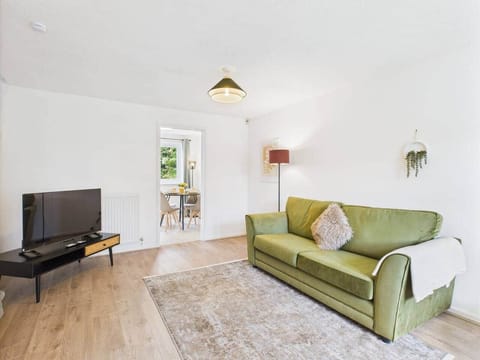 Living room with comfortable sofa facing an led TV, floor lamp for reading and bright space with easy-open curtains