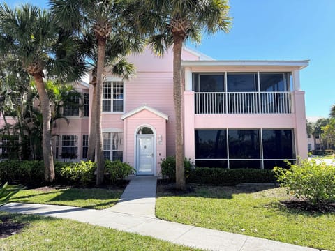 Charming pink ground floor coastal villa with tropical palm trees and enclosed porch just across the street from the beach.