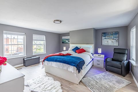 Spacious bedroom with a comfortable queen bed, open clothing area with hangers, and access to a separate workspace with a desk—ideal for work or study.