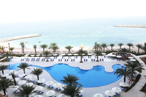 Dive into a palm-lined pool with sparkling sea views.