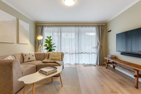 The lounge - sectional sofa, travel books, and sheer curtains letting the light in