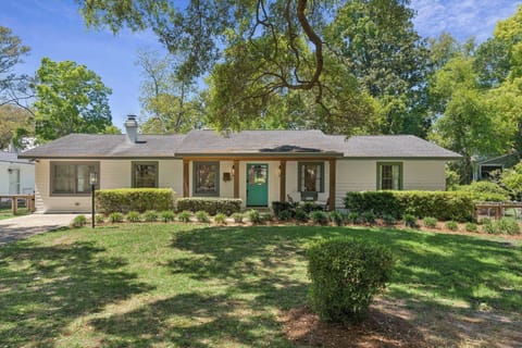 Charming single-story home nestled among mature trees with manicured landscaping and welcoming front entrance.