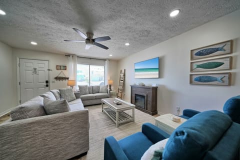 Coastal charm meets modern comfort in this inviting living area. Relax on plush seating and enjoy entertainment on the mounted flat-screen TV.