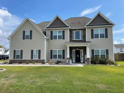 Spacious two-story home with stone accents and welcoming front porch in a peaceful residential neighborhood.
