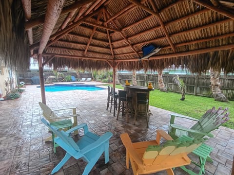 Relaxing private backyard with tiki hut, bar, pool, patio, BBQ pit, and hot tub.
