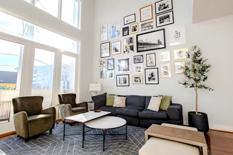 Cozy up in this massive charcoal sofa surrounded by an incredible gallery of framed memories. The olive green armchairs and sleek round coffee tables make this the ultimate spot for group chats.