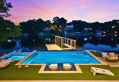 As the sun begins to dip below the trees, the private pool, covered dock, and shimmering waterfront views come together to create a truly unforgettable lakeside setting.