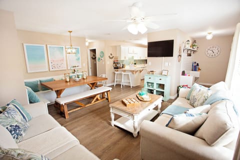 Sun-drenched relaxation. Our open-concept living area features luxury coastal decor, a large Roku Smart TV, and designer furnishings curated for comfort after a long day in the sun.