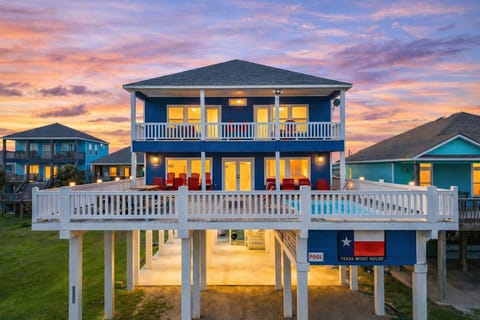 Elevated beachfront vacation rental with large deck and private pool in Port Bolivar, TX. Luxury beach house near Crystal Beach with outdoor seating, coastal views, and sunset sky.