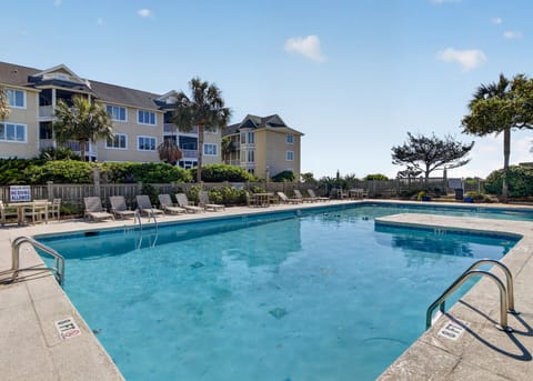 An inviting, sparkling communal pool with resort-style architecture in the background.