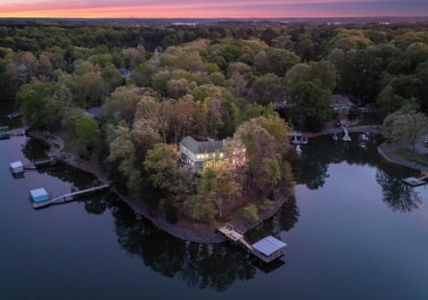 Secluded lakeside peninsula glowing at sunset, with a cozy home tucked among the trees.
