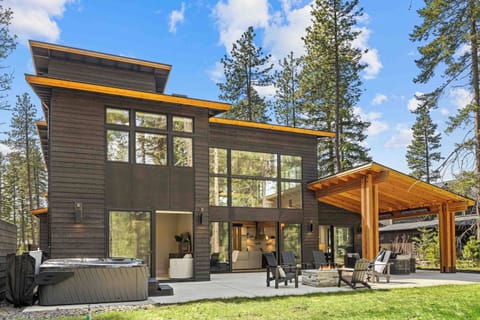Hot tub, fire pit, covered patio, and floor-to-ceiling windows — the back of this house delivers