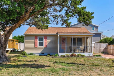 A charming cottage-style vacation rental featuring a welcoming front porch and mature shade tree in a quiet residential neighborhood.