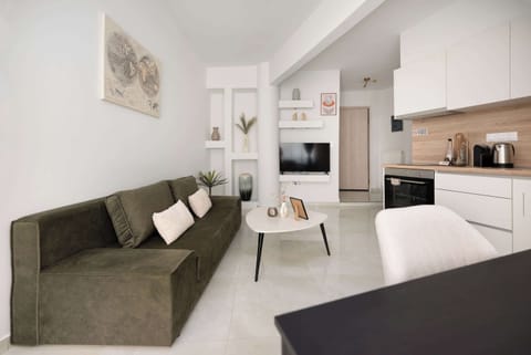 Bright open-plan living area with a stylish sofa and modern kitchen. Clean lines, warm tones, and thoughtful decor create a cozy yet elegant space—perfect for relaxing, dining, and enjoying your stay.