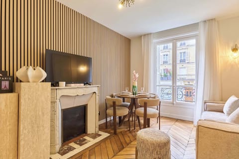 Salon avec canapé, espace repas, cuisine ouverte et TV
