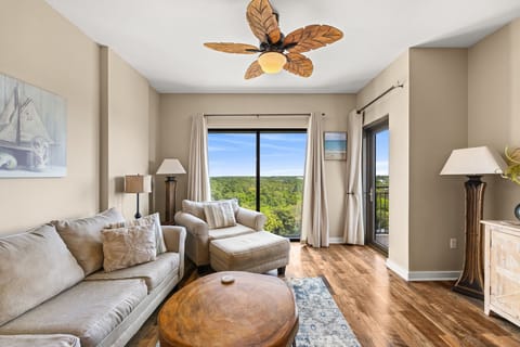 Unwind in your elegant living room with tropical ceiling fan and breathtaking forest views through floor-to-ceiling windows.