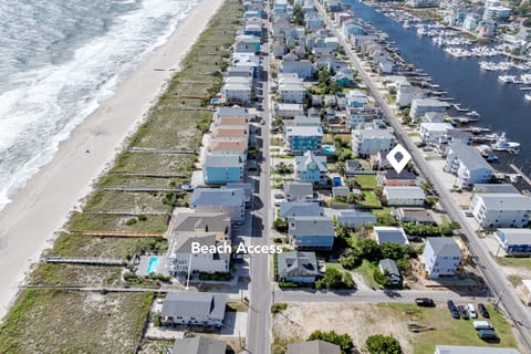 Aerial view of beachfront community with direct beach access, marina, and coastal neighborhood featuring vacation rental properties.