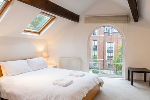 Wake under exposed beams with an arched window flooding the mezzanine in warm light.