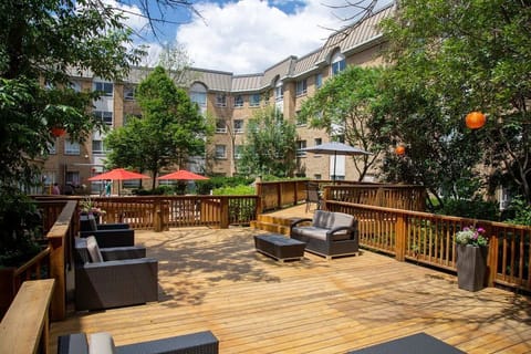 Wooden deck with lounge chairs and red umbrella shading — the courtyard wraps around the hotel for outdoor breaks throughout the day.