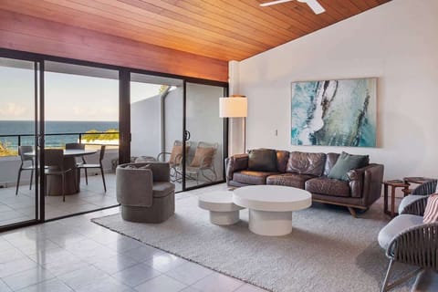 Unwind in the open-plan living room with sweeping ocean views and warm timber accents—perfect for sunset lounging.