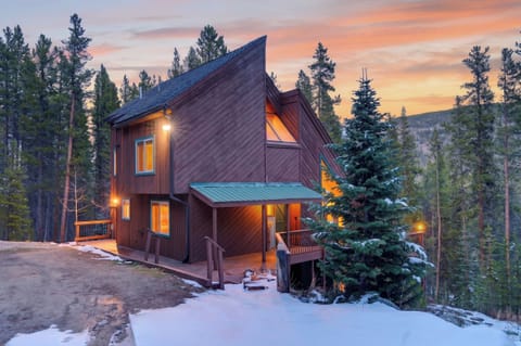 Cozy mountain cabin with warm glowing interiors and scenic forest views at sunset.